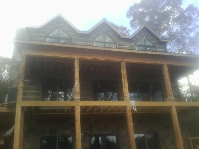 Dormers and porch framing on a large log home under construction — Roof Coating work by our crew in Louviers