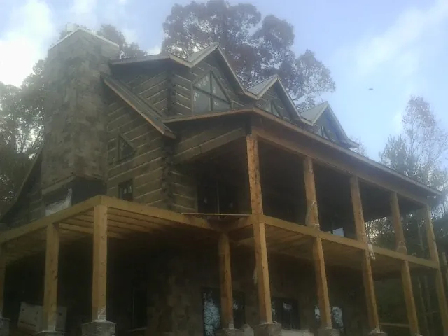 Stone chimney and dormers on a large log home with a timber porch in Louviers