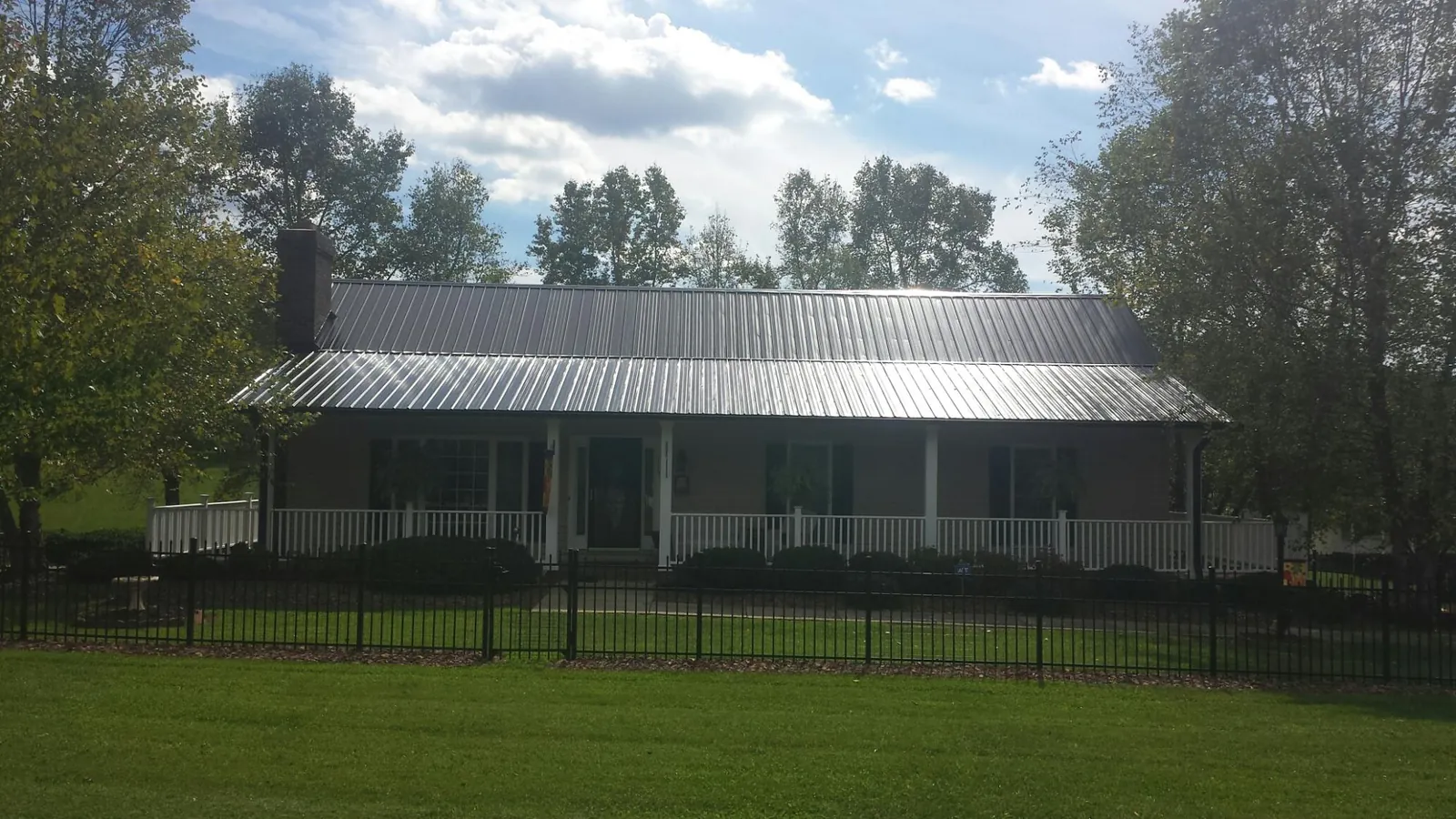 Gray metal roof on a brick ranch with a full width front porch — Gutter Guard Installation work by our crew in Louviers