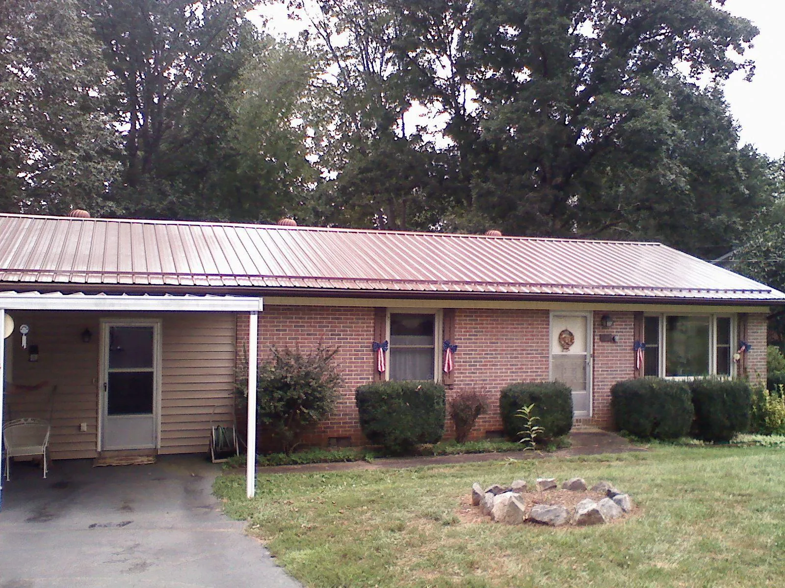 Bronze metal roof and carport on a brick ranch home — Roof Repair work by our crew in Louviers