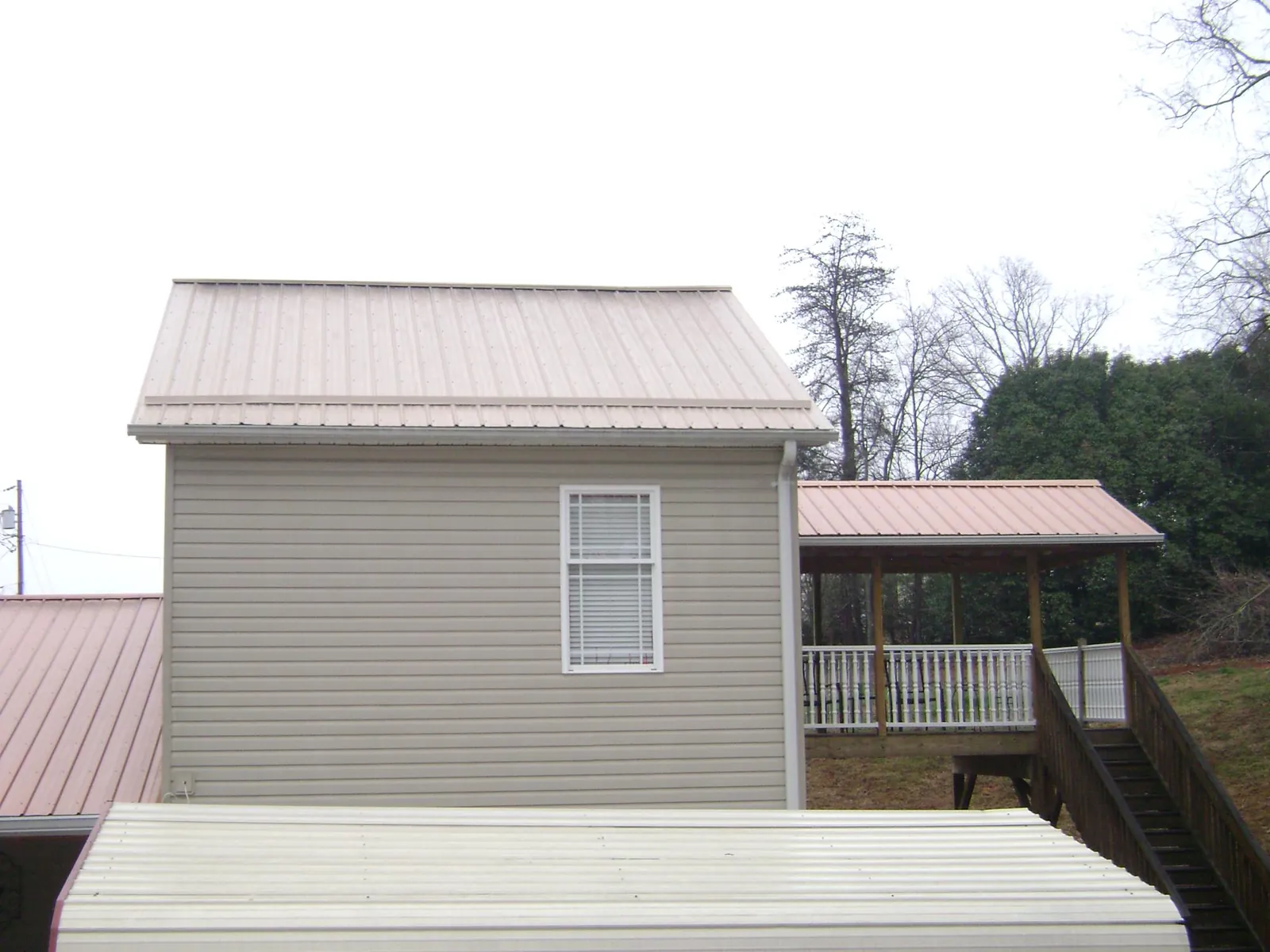 Tan metal roofs on a two story addition and attached porch, from a Roof Replacement job in Louviers