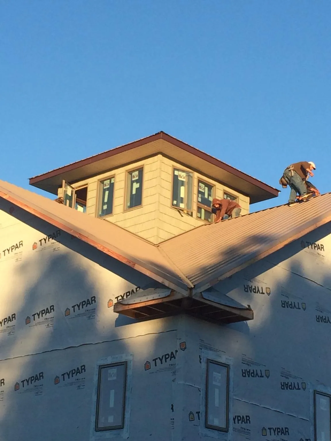Roofers working around a rooftop cupola on a new metal roof at sunset — Roof Waterproofing in Louviers by Roofing Brothers